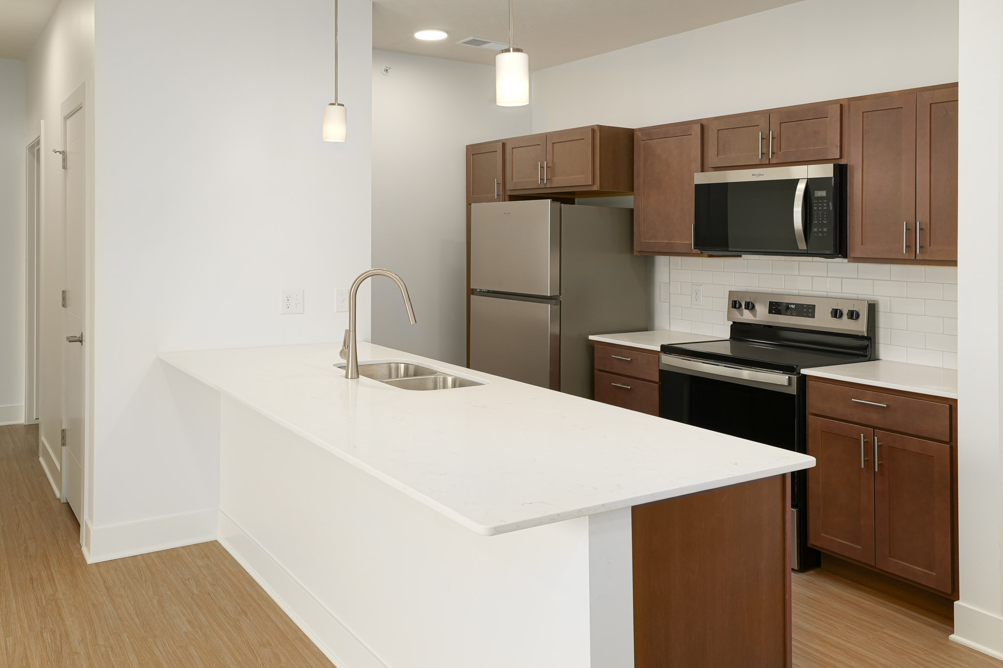 Kitchen featuring quartz island, subway tile backsplash, stainless steel appliances, and pendant lighting.