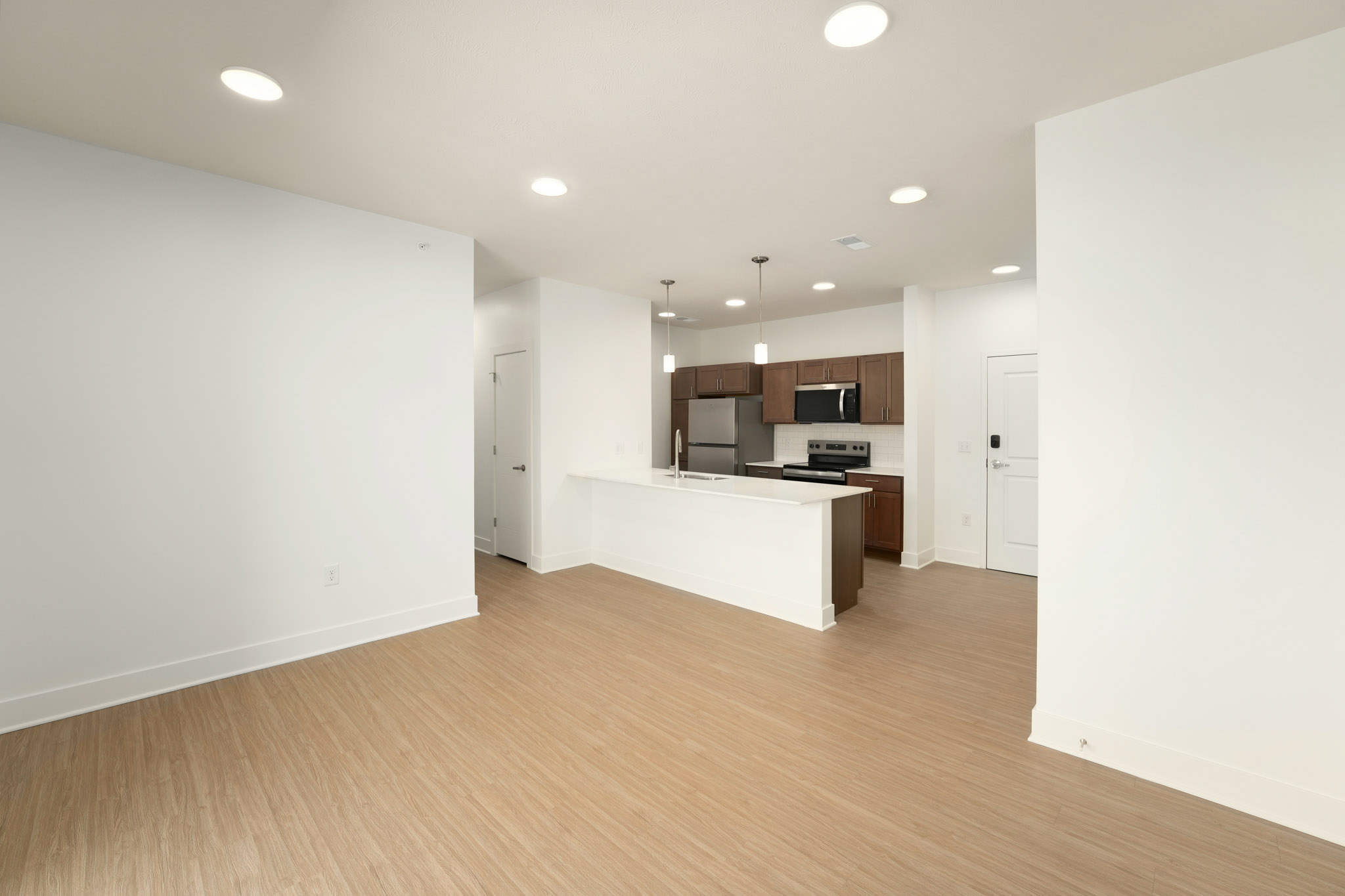 Open living area with wood-style flooring and kitchen featuring oversized island.