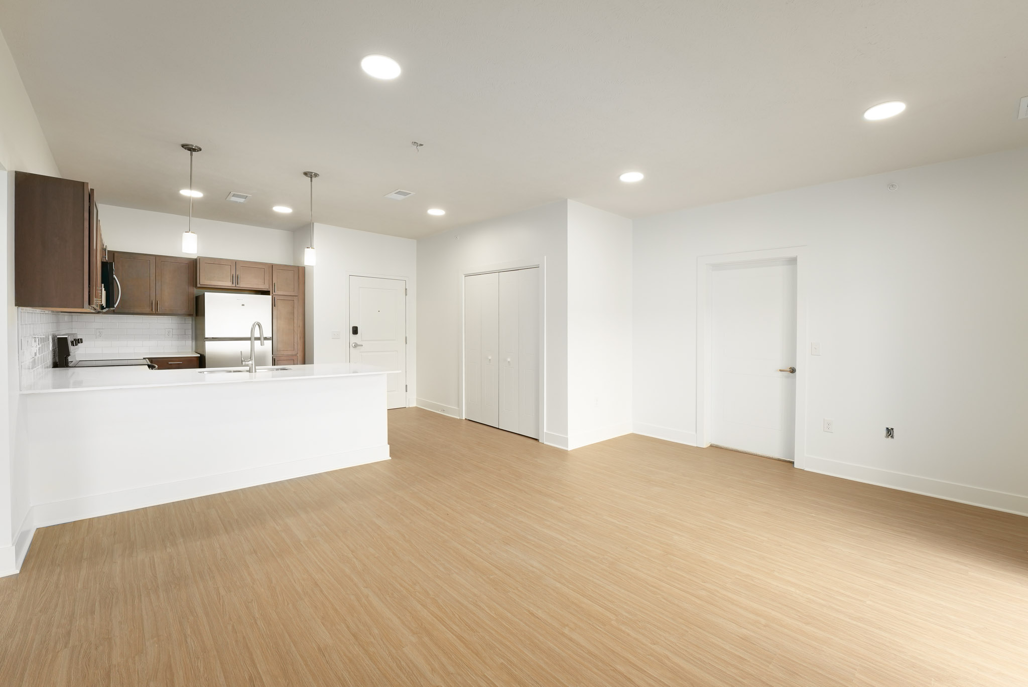 Open-concept living area with wood-style flooring and adjacent kitchen island.
