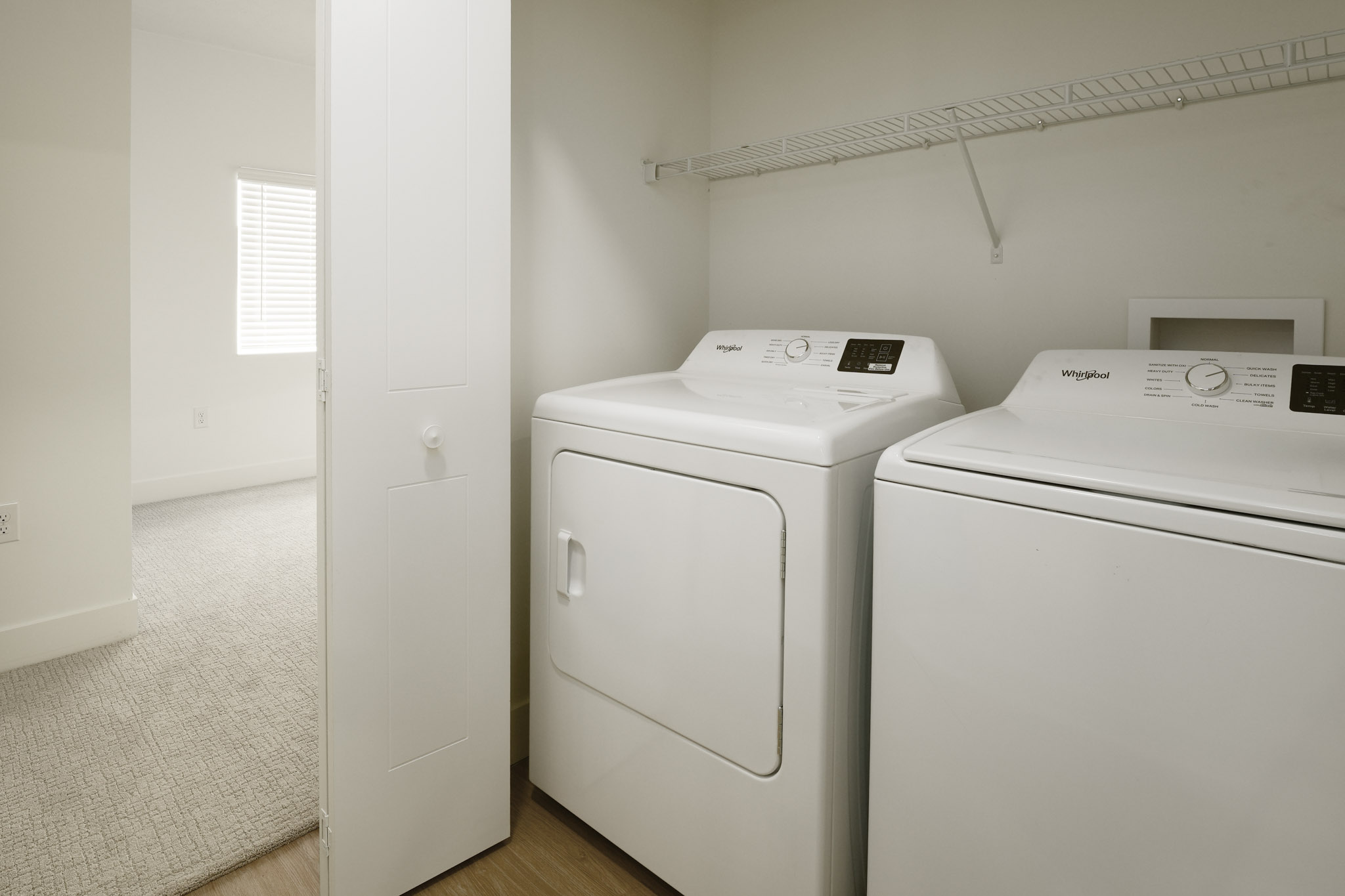 In-home laundry area with full-size washer, dryer, and wire shelving storage.