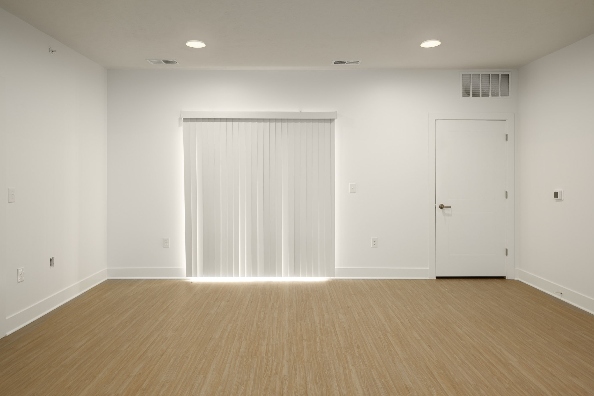 Spacious living room with wood-style flooring, recessed lighting, and sliding glass door.