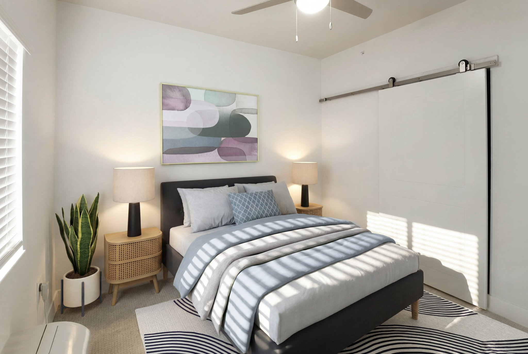 Staged bedroom with ceiling fan, barn-style closet door, and carpet flooring.