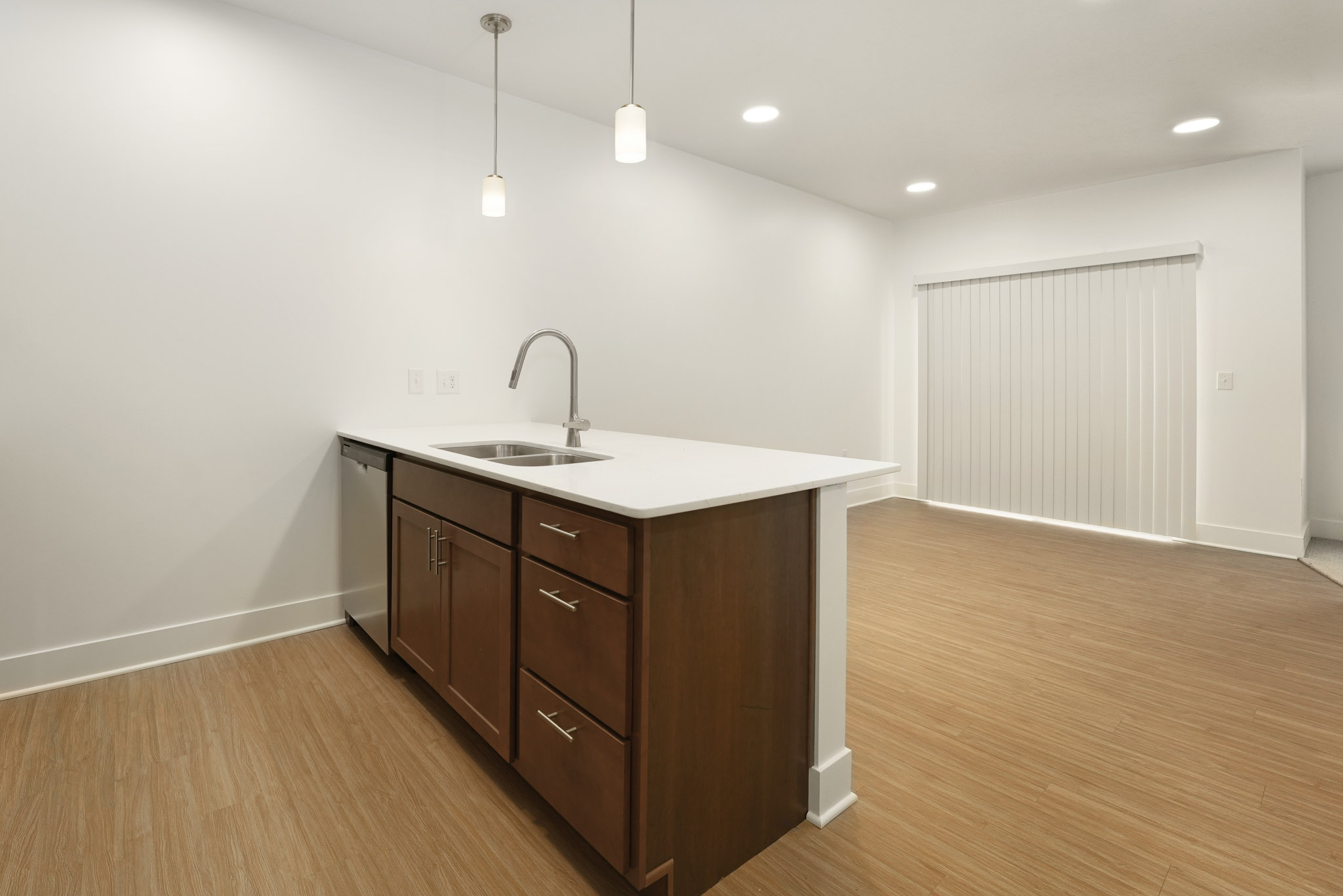 Open kitchen with quartz island, pendant lighting, wood cabinetry, and adjacent living area.