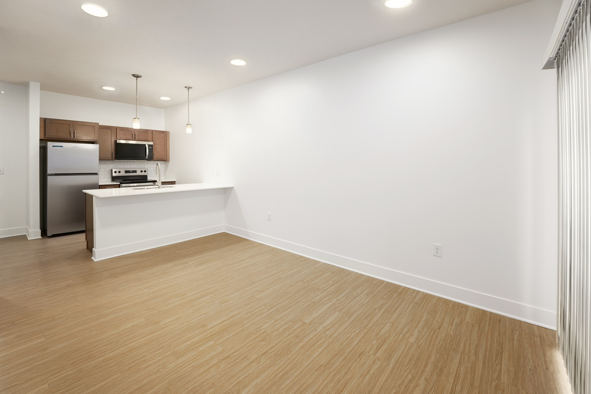 Open-concept living area with wood-style flooring and kitchen featuring oversized island.