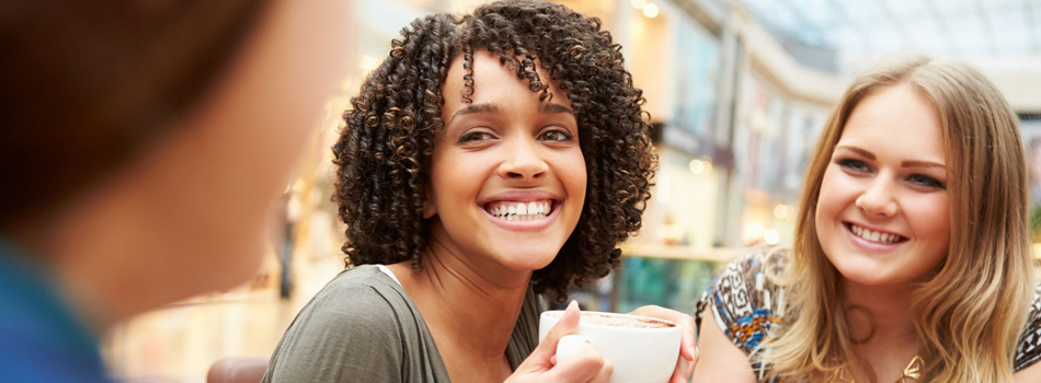 A black woman smiles while holding a cup of coffee