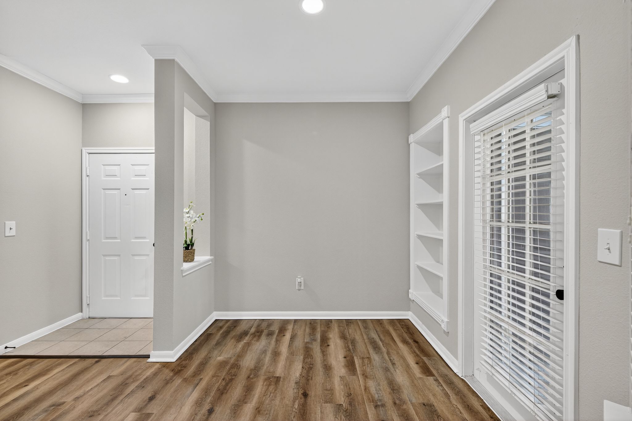 Empty bedroom with two windows, beige walls, carpeted flooring, and a ceiling fan adding light to the space