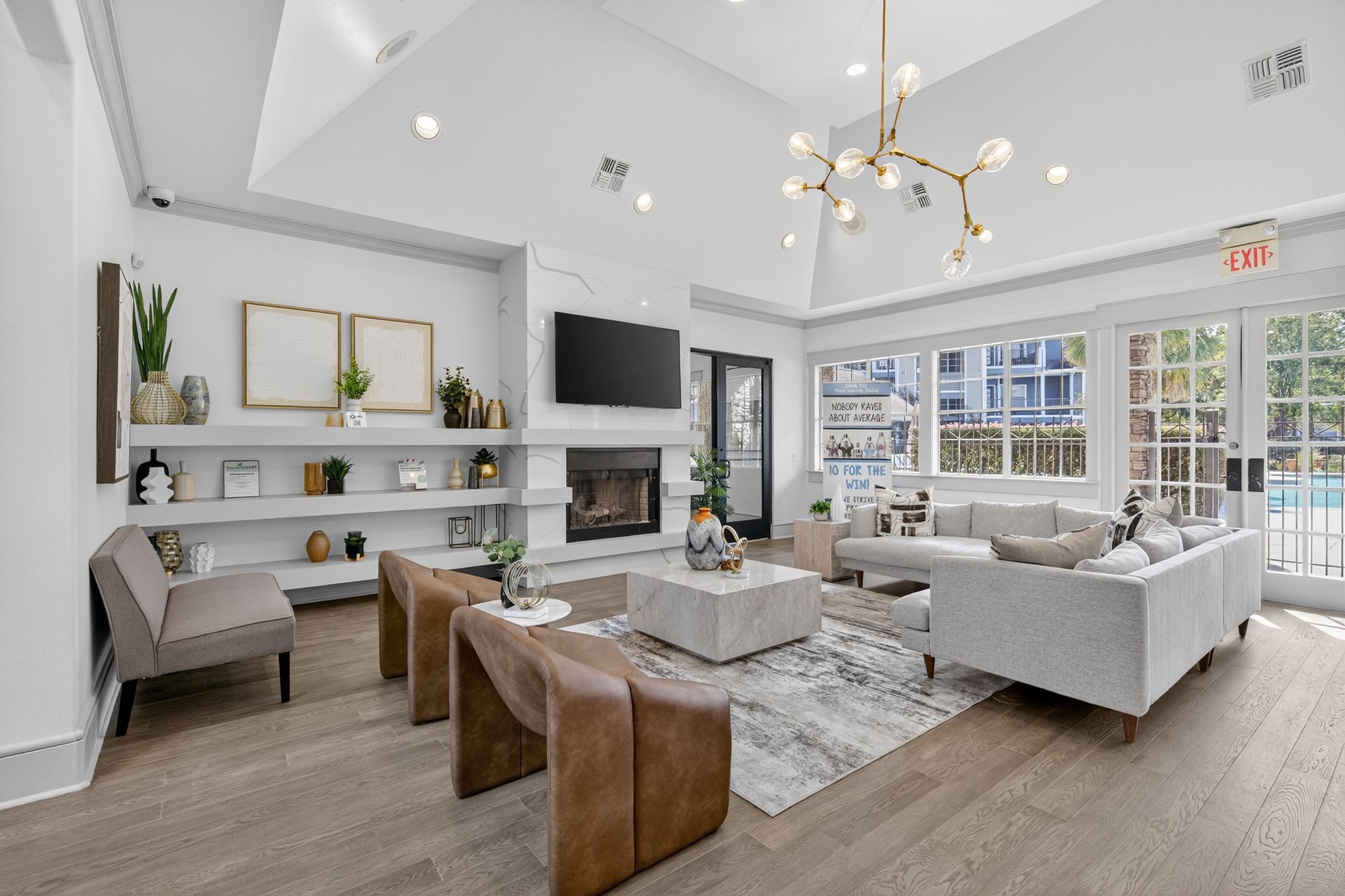 Contemporary community club room featuring a fireplace wall, built-in shelving, plush seating, and large windows for natural light