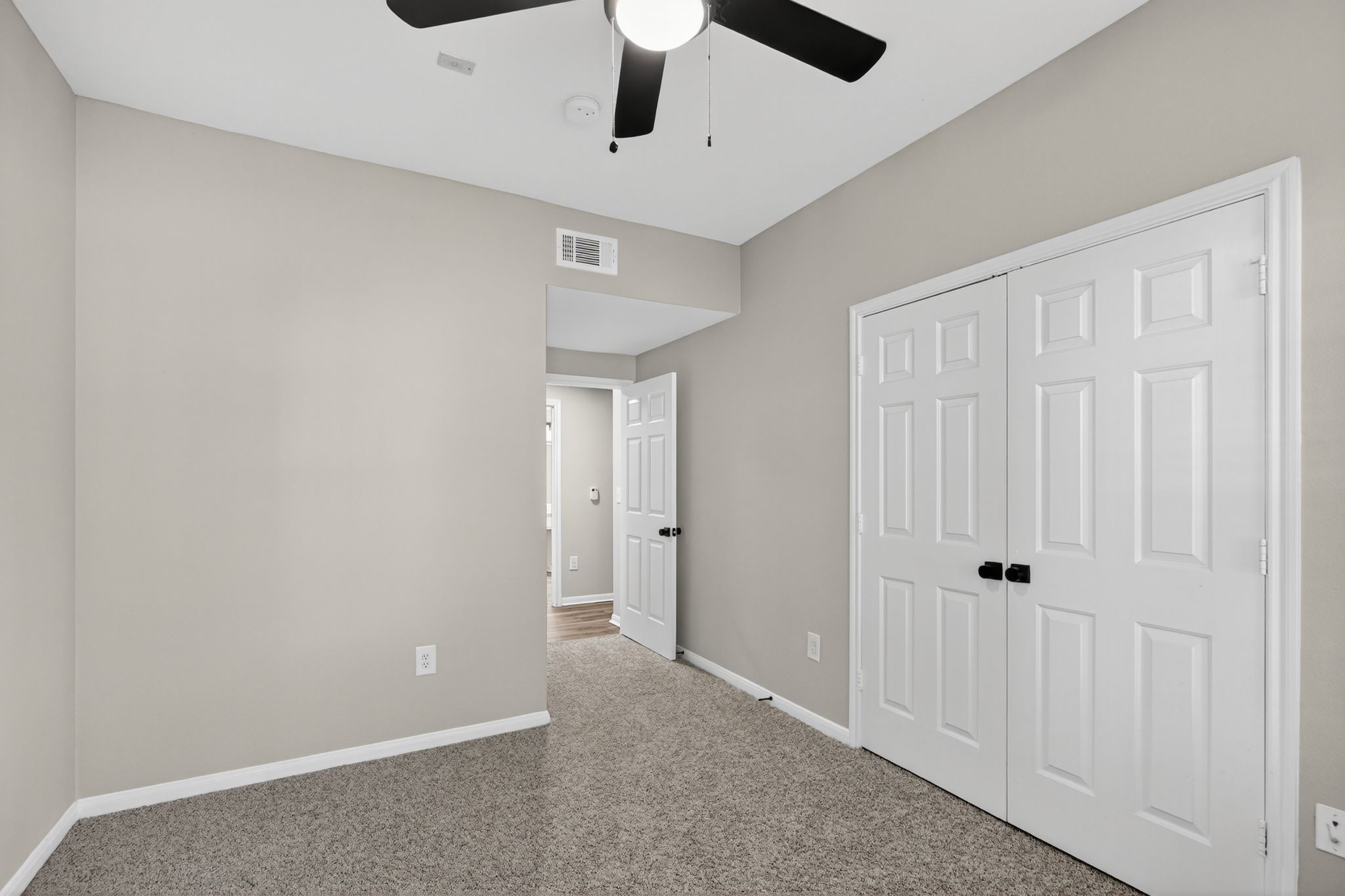 Bedroom with carpet flooring, neutral walls, double door closet, and a ceiling fan centered above the room