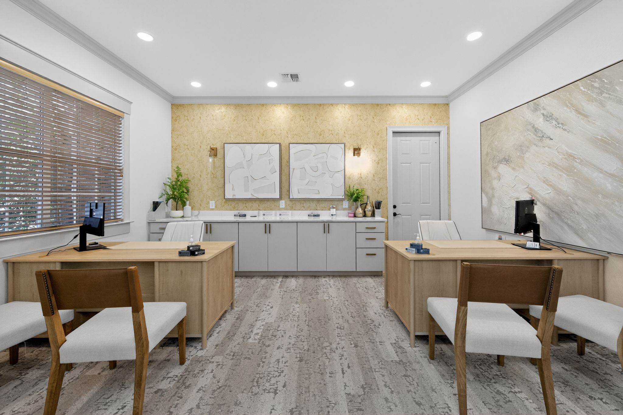 Stylish leasing office with dual desks, contemporary artwork, storage cabinetry, and soft lighting in a welcoming professional space