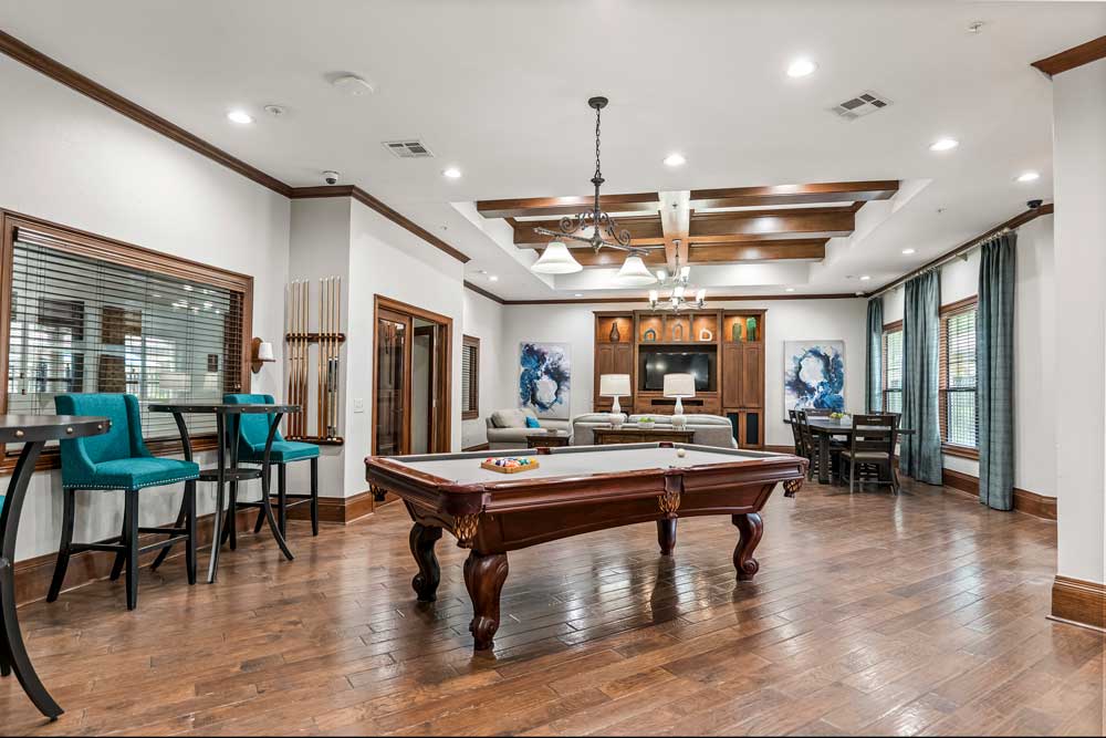 Community game room with pool table, high-top seating, lounge area, and open layout connecting to dining and entertainment space