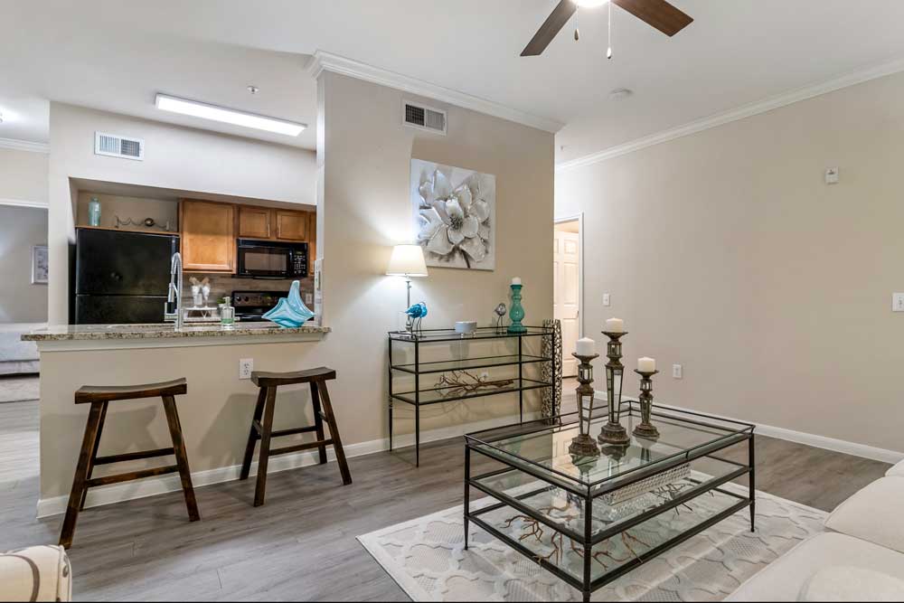 Open living and kitchen area with breakfast bar, bar stools, decorative console table, wall art, and wood style flooring