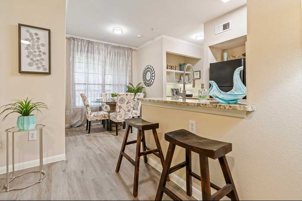 Open-concept kitchen and dining area with breakfast bar, granite countertops, bar stools, pendant lighting, and window seating