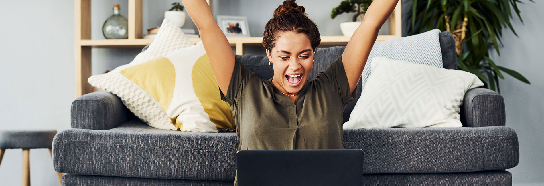 A woman happily cheering in front of her laptop