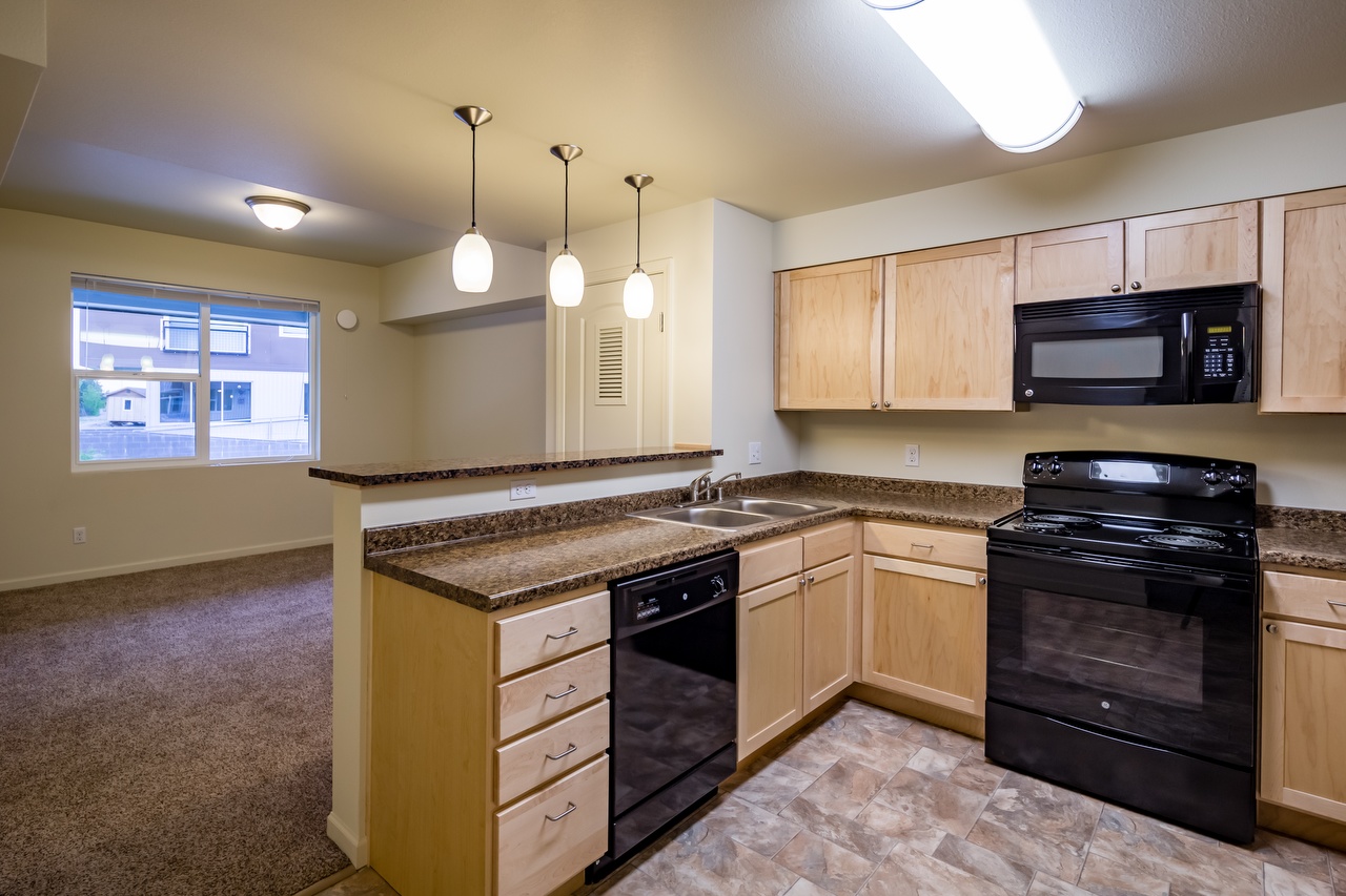 1BR Kitchen with Modern Counter Lighting and Black Appliances