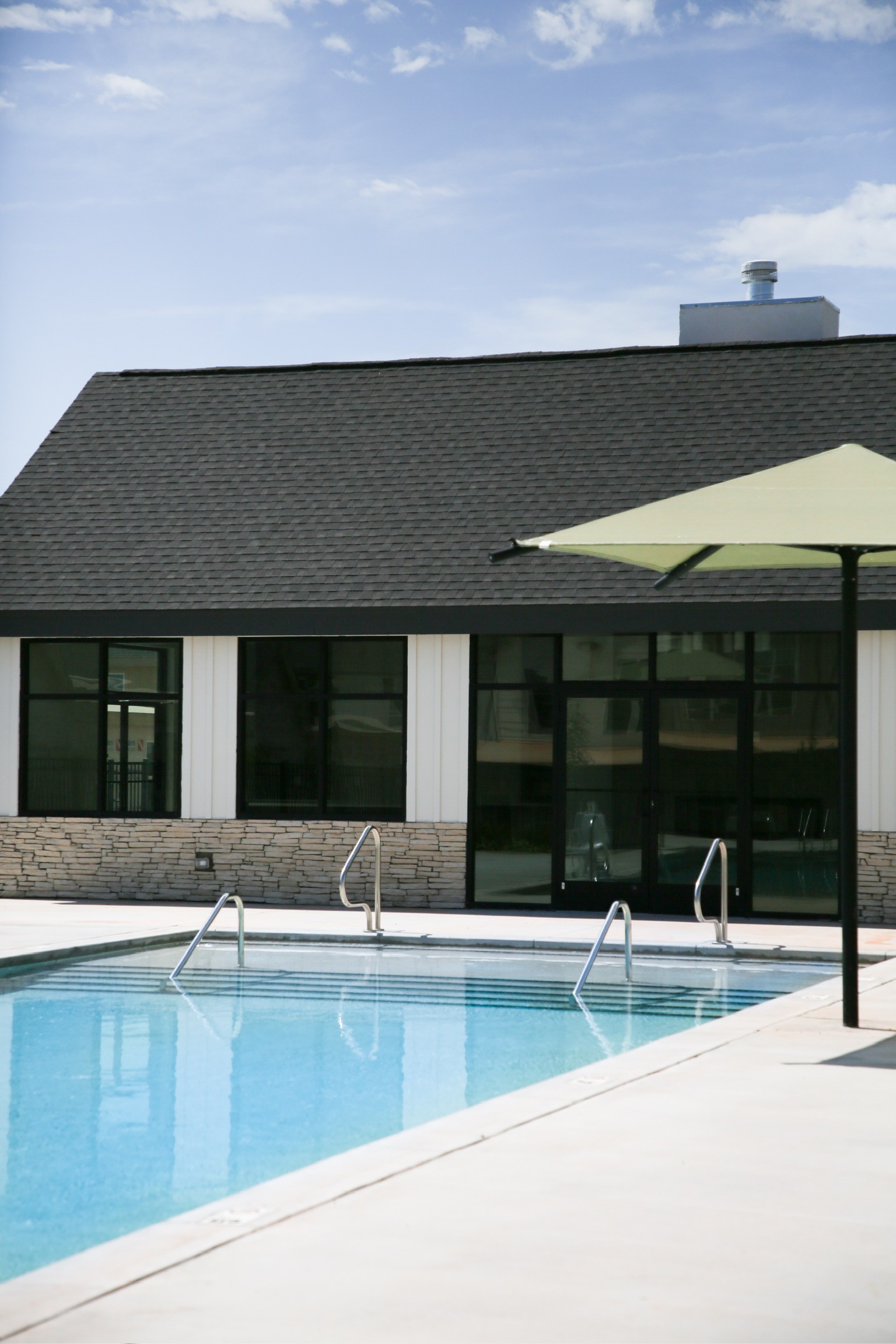 Outdoor resort-style pool with umbrella seating and large windows overlooking the water at the community clubhouse