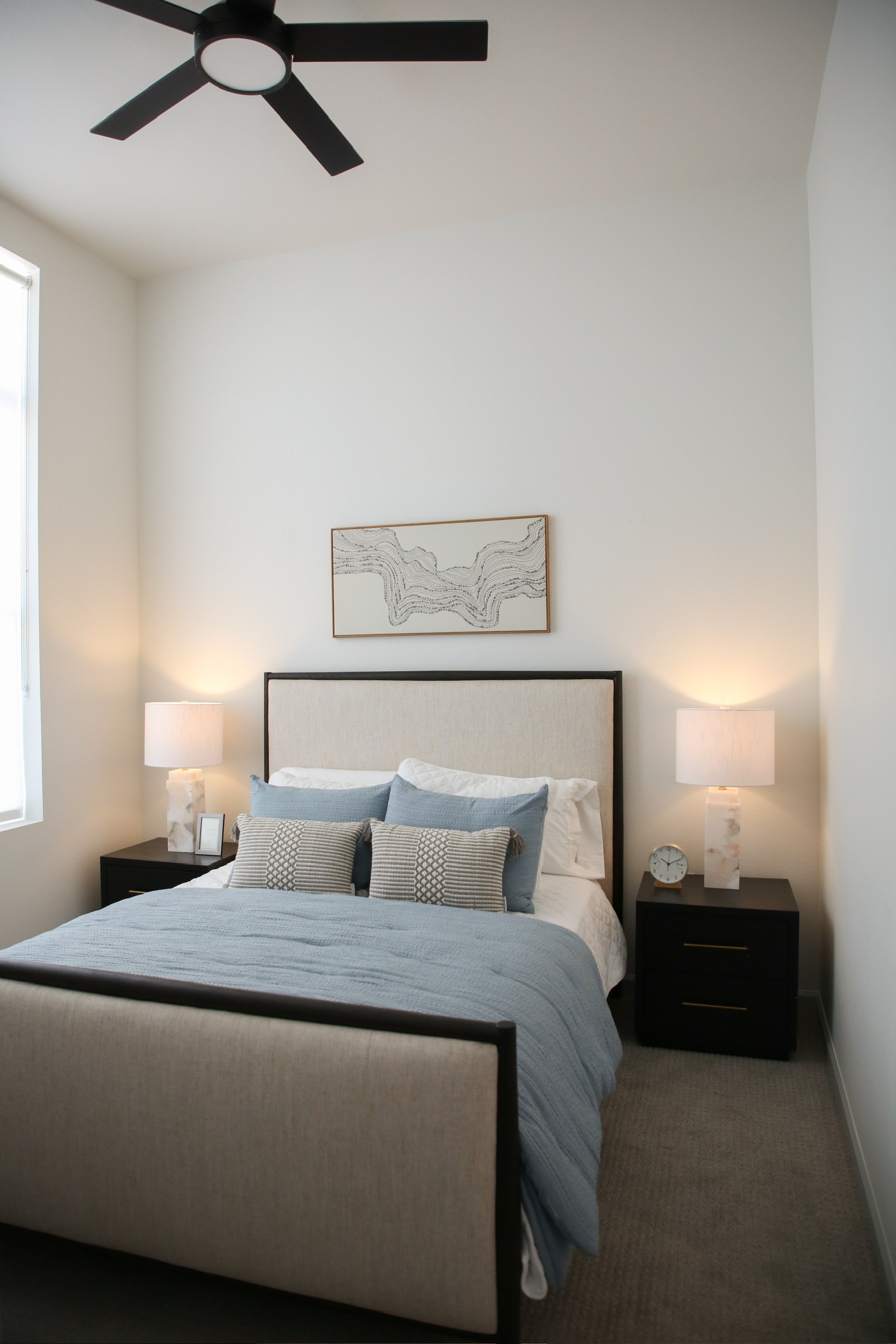  Elegant primary bedroom with upholstered bed frame, matching nightstands, soft lighting, and high ceilings
