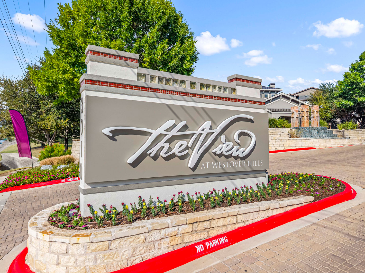 The View at Westover Hills entrance monument sign surrounded by colorful flower beds, a stone retaining wall, and brick pavers