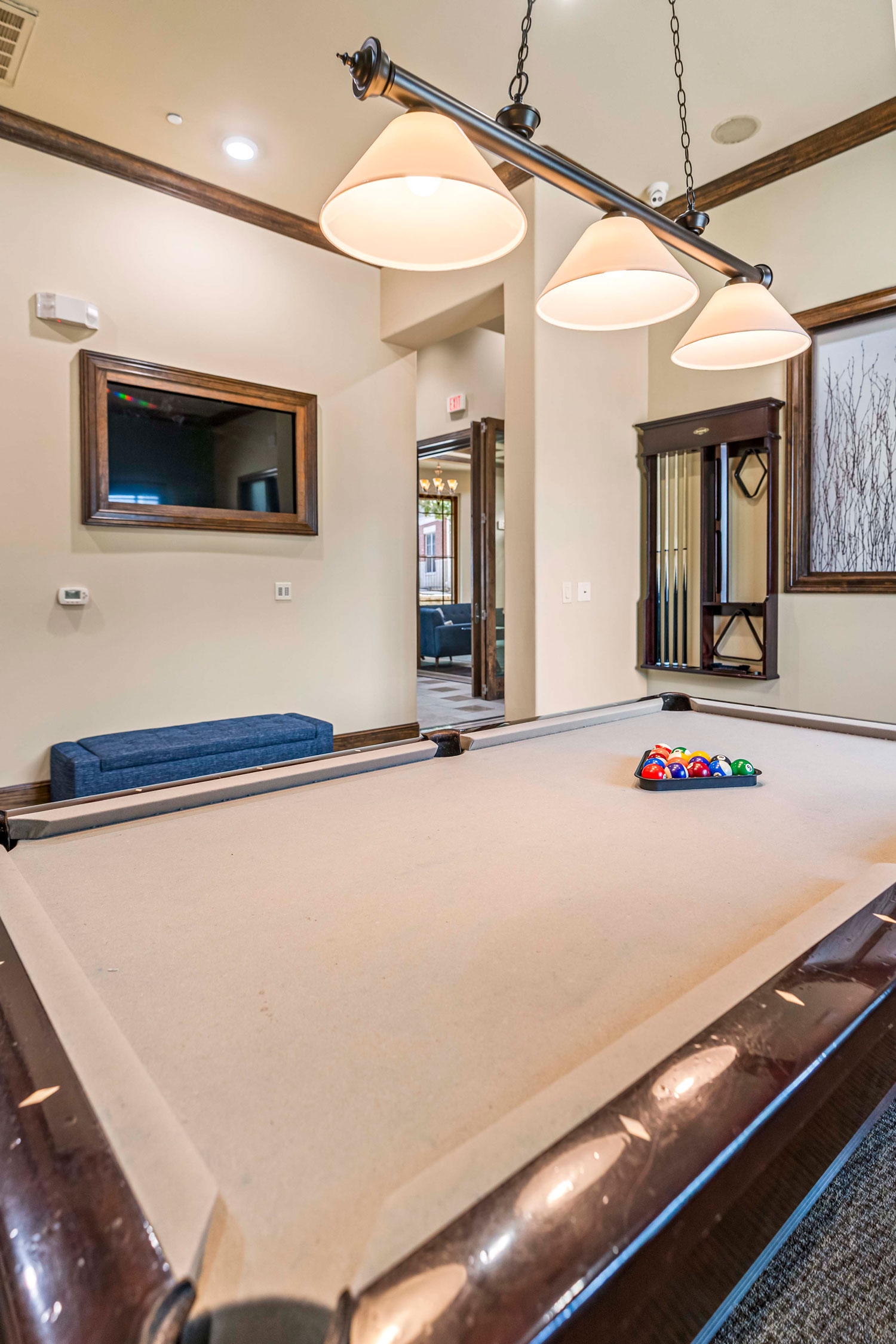 Clubhouse game room with billiards table, pendant lighting, wall mounted television, and wood trim accents