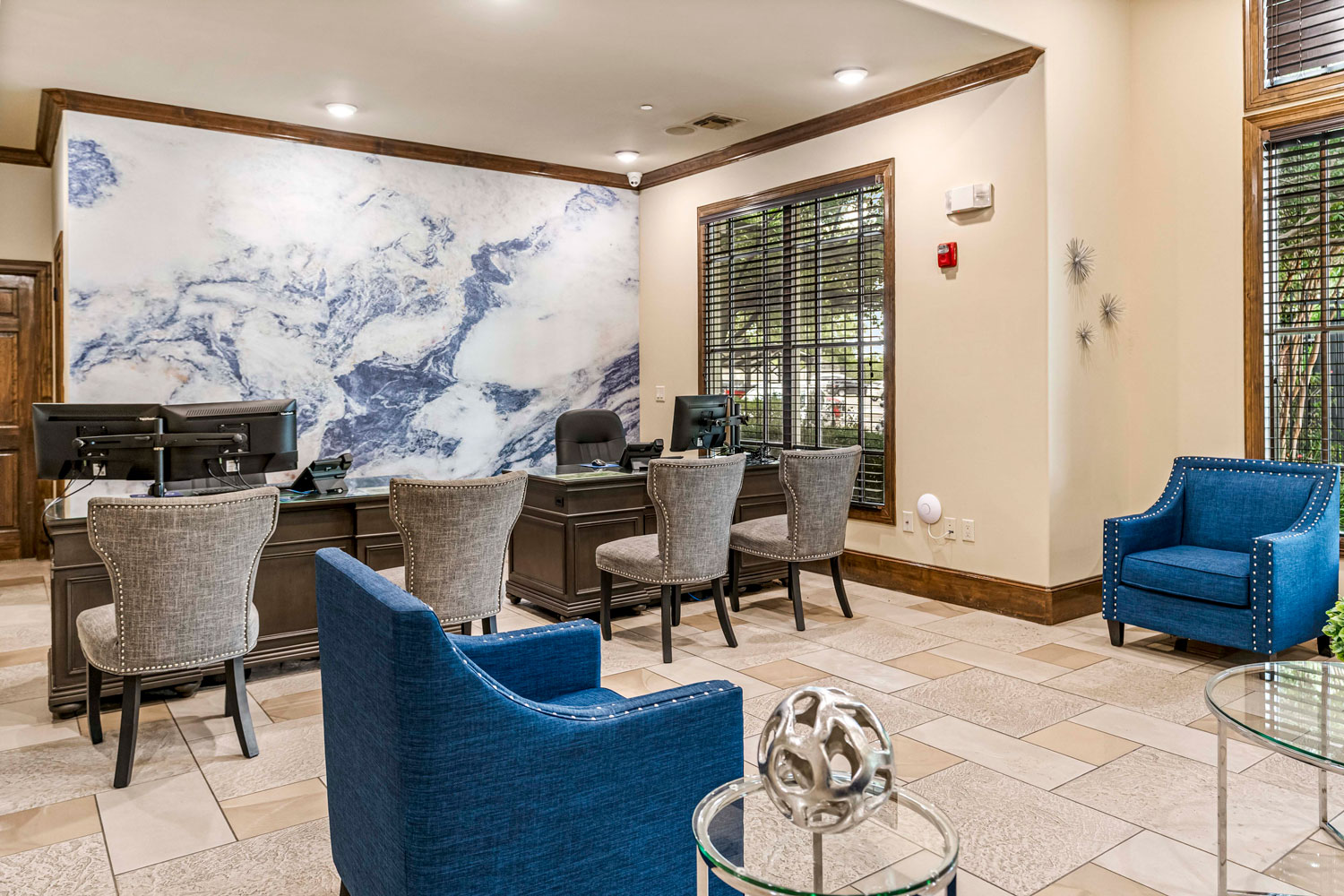 Leasing office interior with service desk, guest seating, marble accent wall, large windows, and tiled clubhouse flooring