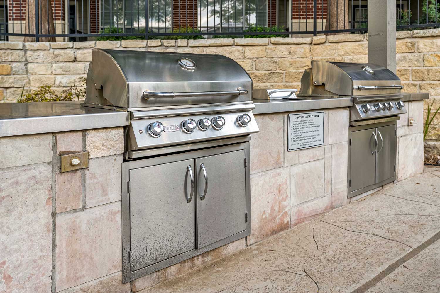 Outdoor stainless steel gas grills with prep counters and stone surround in covered apartment grilling pavilion