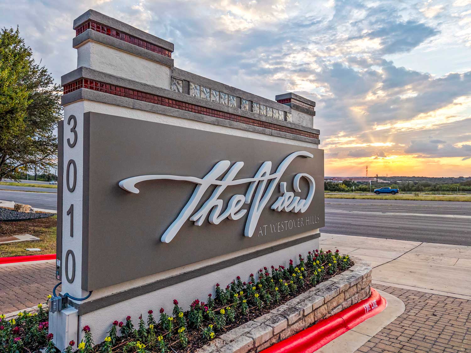 The View at Westover Hills community entrance monument sign at address 3010, lit by a dramatic orange sunset sky