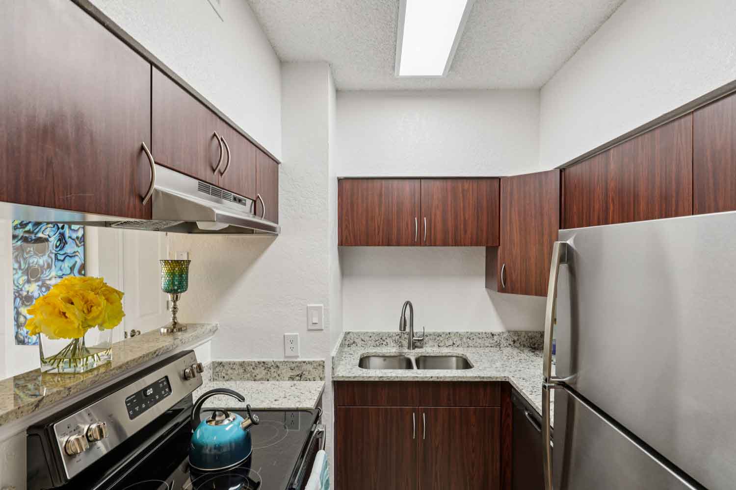 Modern kitchen with granite countertops, dark wood cabinets, stainless steel refrigerator, and breakfast bar with seating