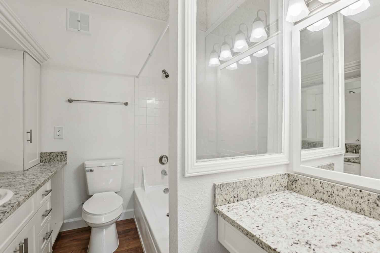 Full bathroom with granite vanity, framed mirrors, toilet, and tiled tub and shower combination