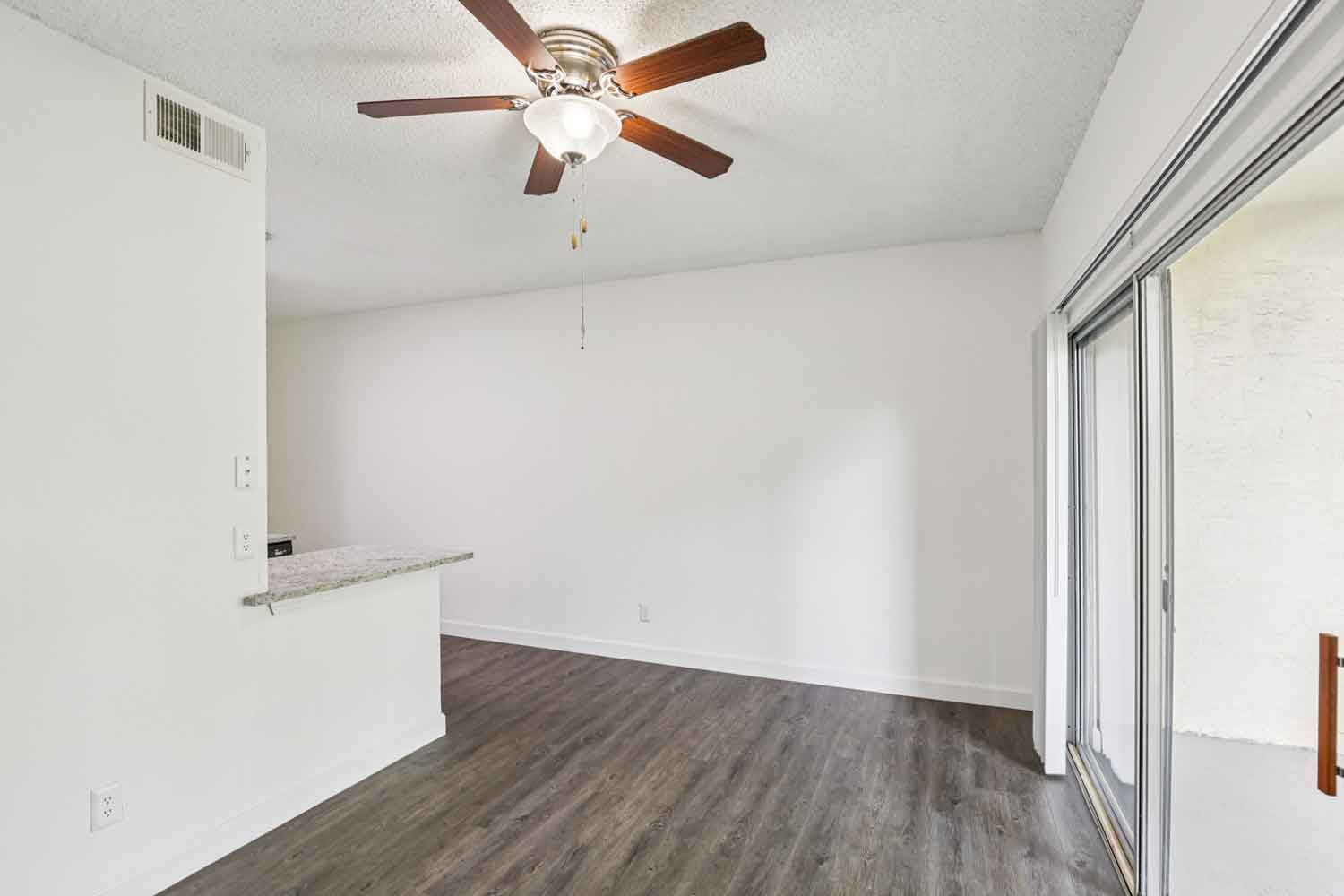 Living room with breakfast bar pass through, wood style floors, ceiling fan, and sliding glass doors to patio