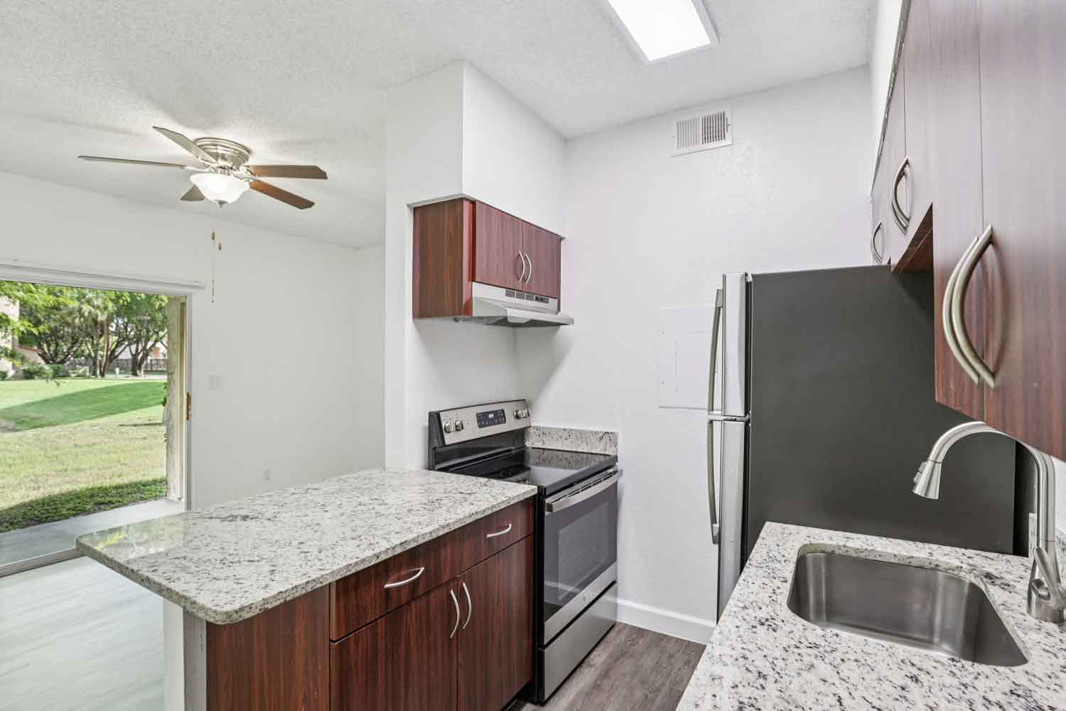 Galley kitchen with granite countertops, stainless steel refrigerator, dishwasher, wood cabinets, and modern faucet
