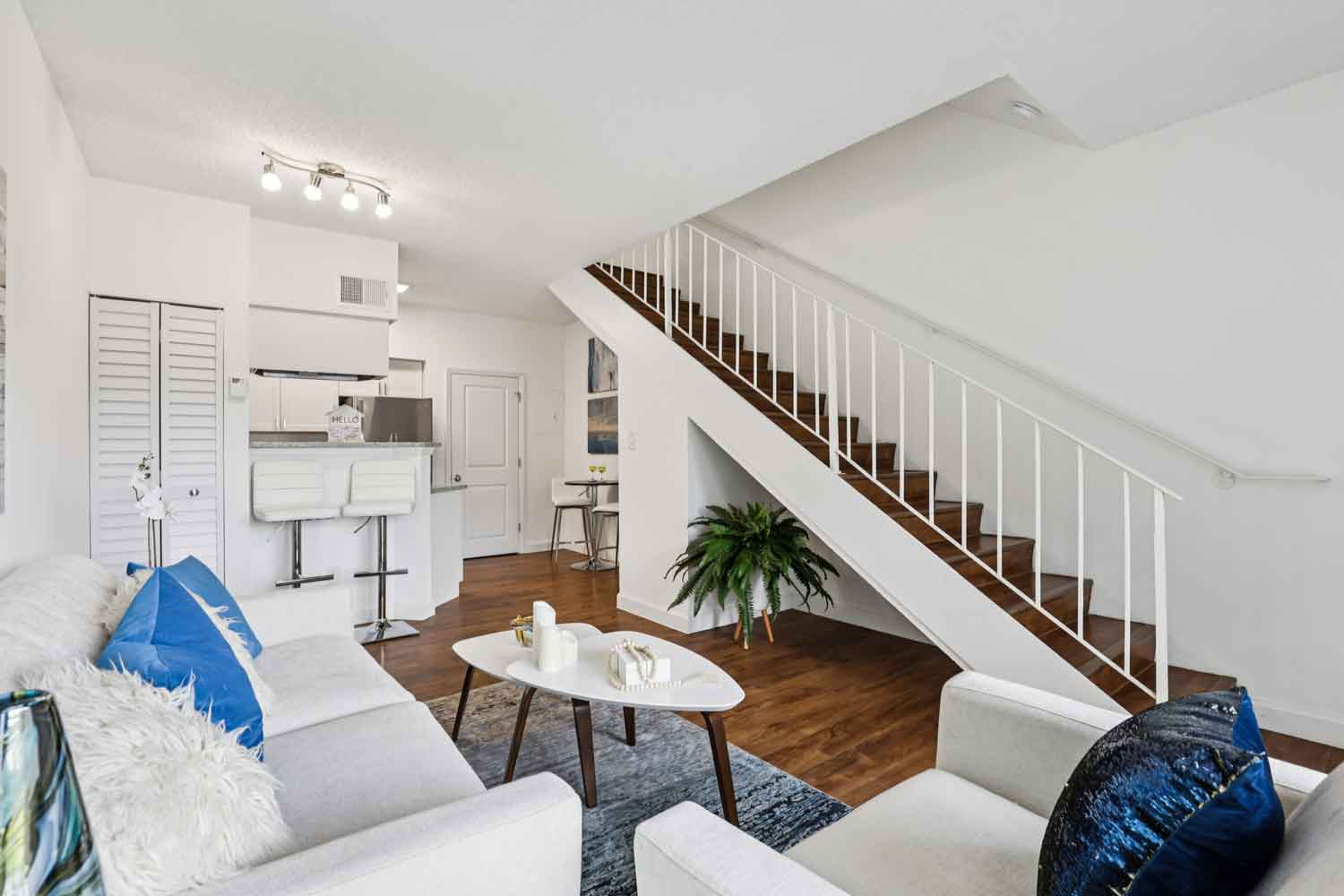 Open concept living space with staircase, sofa, accent chairs, breakfast bar seating, and kitchen in background