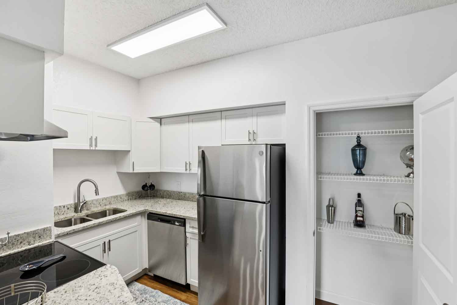 Kitchen with double sink, granite counters, stainless steel refrigerator, dishwasher, and open pantry shelving