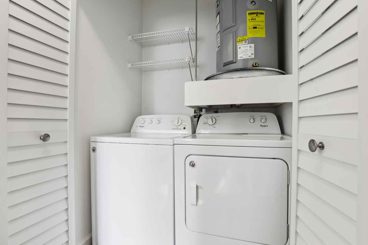 Laundry closet with full size washer and dryer, water heater above, and white wire shelving for extra storage