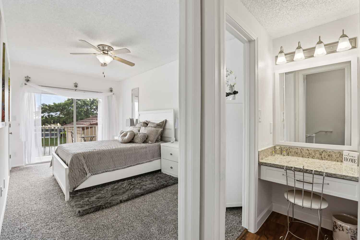 Bedroom and vanity area with granite countertop, framed mirror, modern light fixture, and sliding balcony doors
