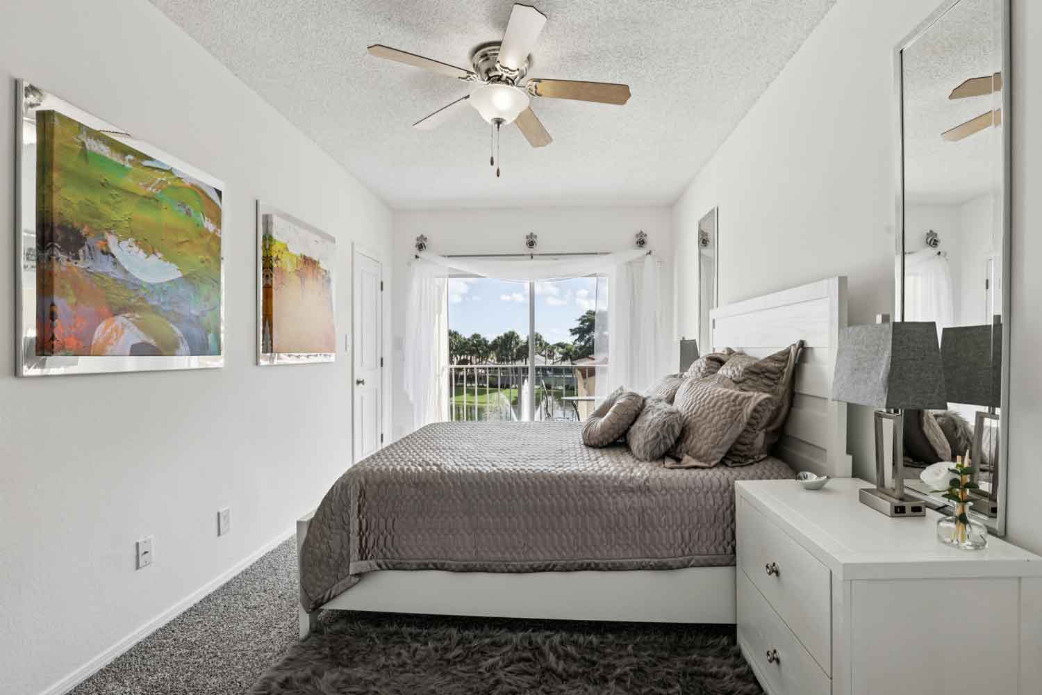 Bedroom featuring white bed frame, layered pillows, abstract wall art, and doorway leading to closet and bath