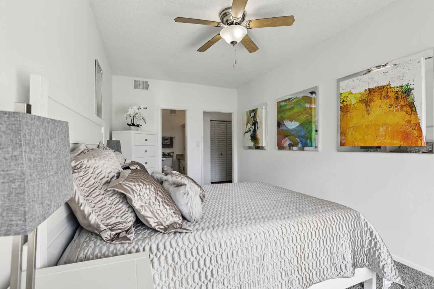 Bedroom with large window and sheer curtains, balcony view, white nightstand, and plush gray area rug