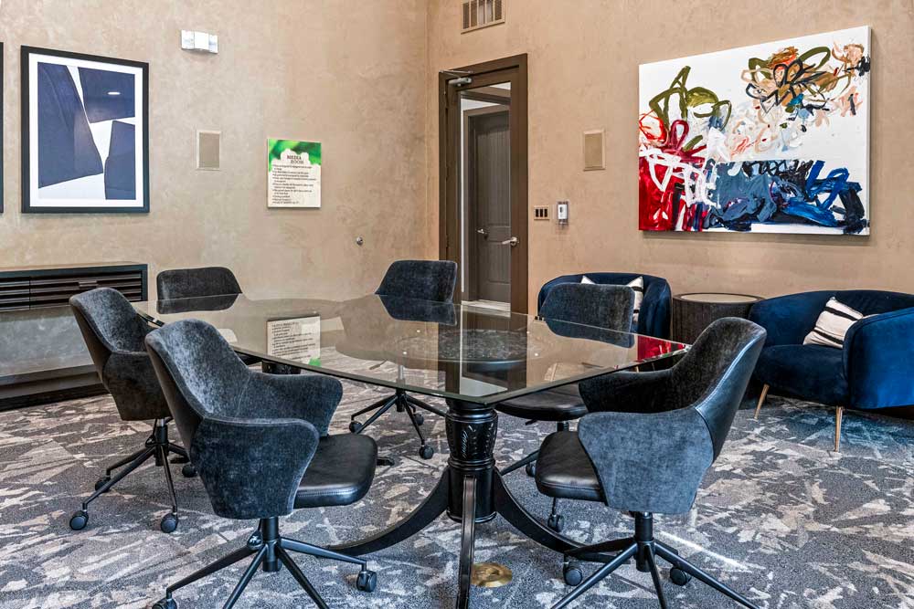 Sleek meeting space with velvet chairs, abstract artwork, and a seating nook with blue armchairs and pillows
