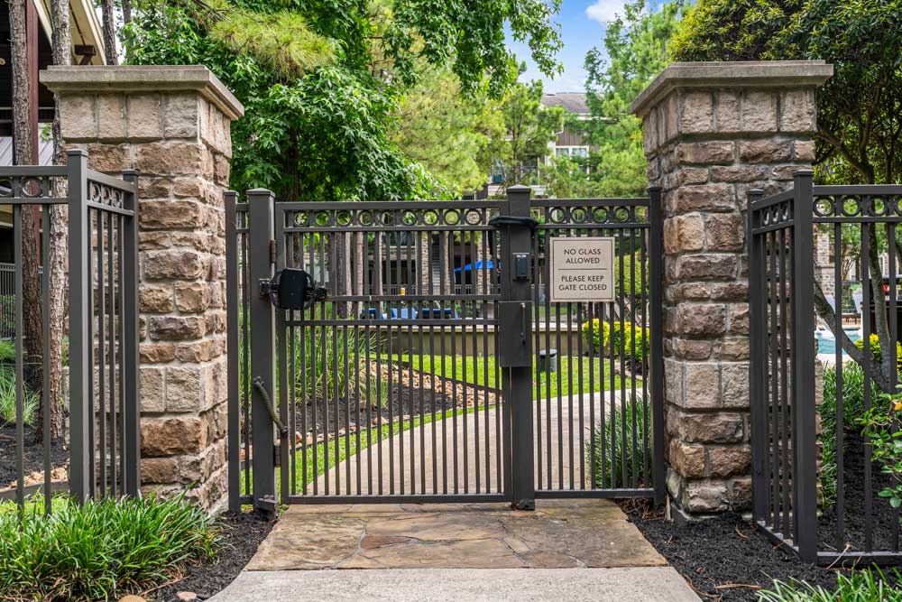Stone and metal gate leading to the pool and outdoor area with a sign requesting to keep the gate closed